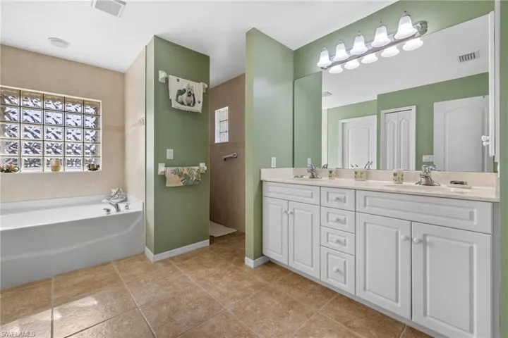Bathroom featuring vanity, tile patterned floors, and a tub to relax in