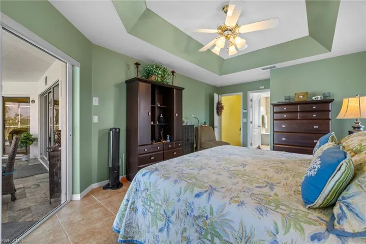 Bedroom featuring a raised ceiling, access to exterior, and ceiling fan