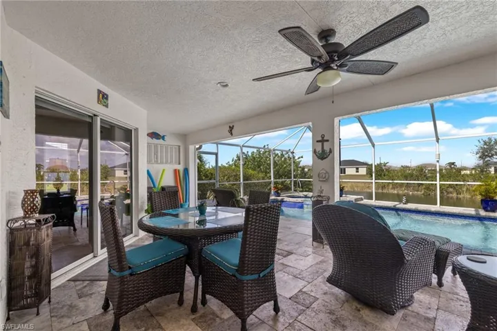 Sunroom featuring a pool, a water view, a wealth of natural light, and ceiling fan