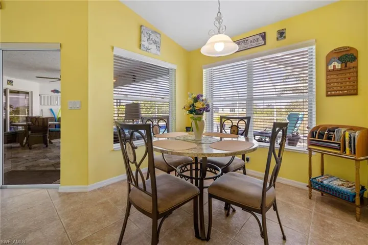 Dining space with light tile patterned floors, vaulted ceiling, and ceiling fan