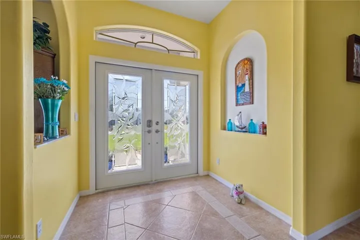 Doorway to outside with french doors, a wealth of natural light, and light tile patterned floors