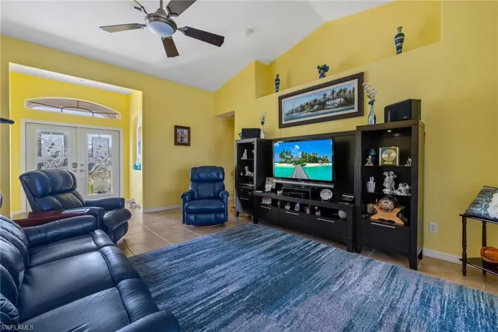 Living room featuring tile patterned flooring, vaulted ceiling, french doors, and ceiling fan