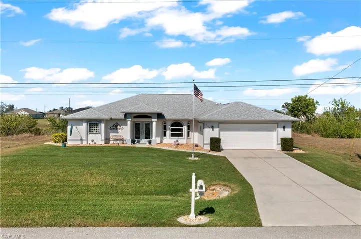 Single story home with french doors, a garage, and a front lawn