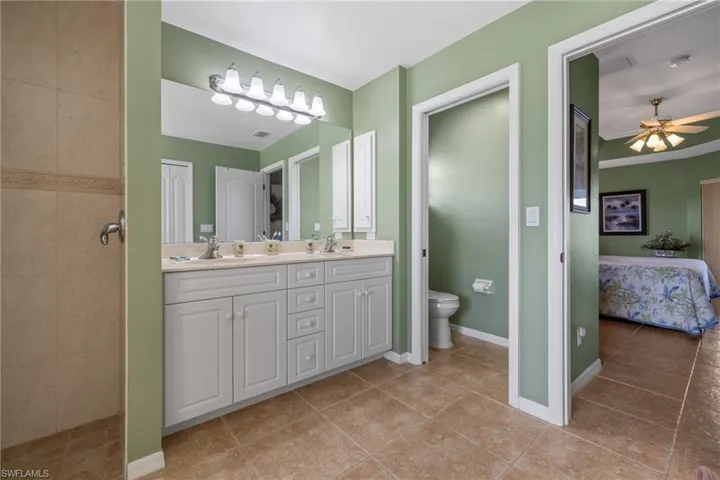 Bathroom with vanity, tile patterned flooring, toilet, and tiled shower