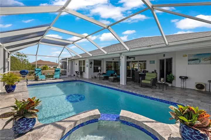 View of pool featuring glass enclosure, an in ground hot tub, ceiling fan, an outdoor living space, and a patio