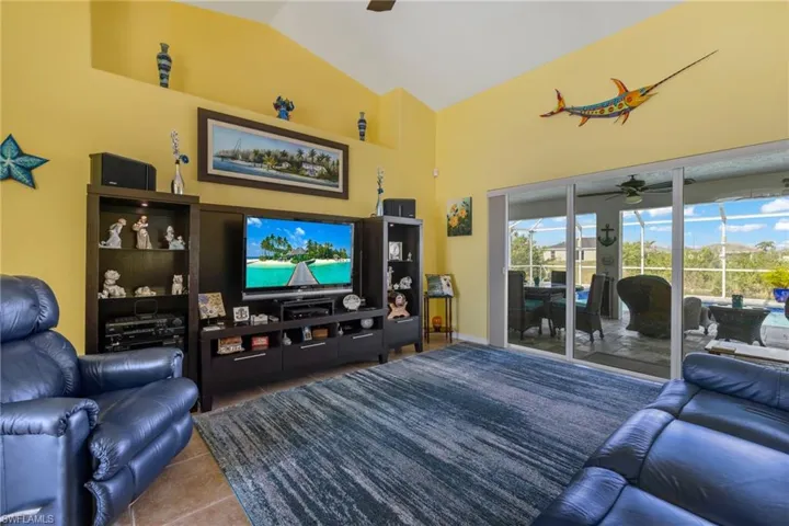 Tiled living room featuring vaulted ceiling and ceiling fan