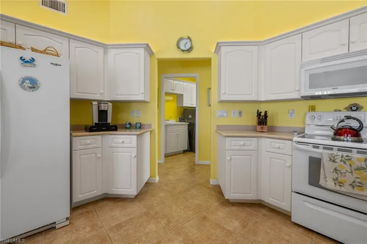Kitchen with white cabinetry, white appliances, and light tile patterned floors