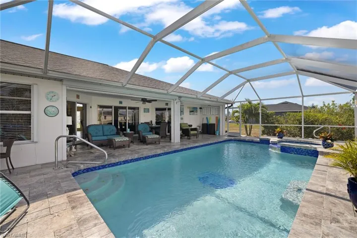 View of swimming pool featuring a patio area, glass enclosure, an in ground hot tub, ceiling fan, and an outdoor living space