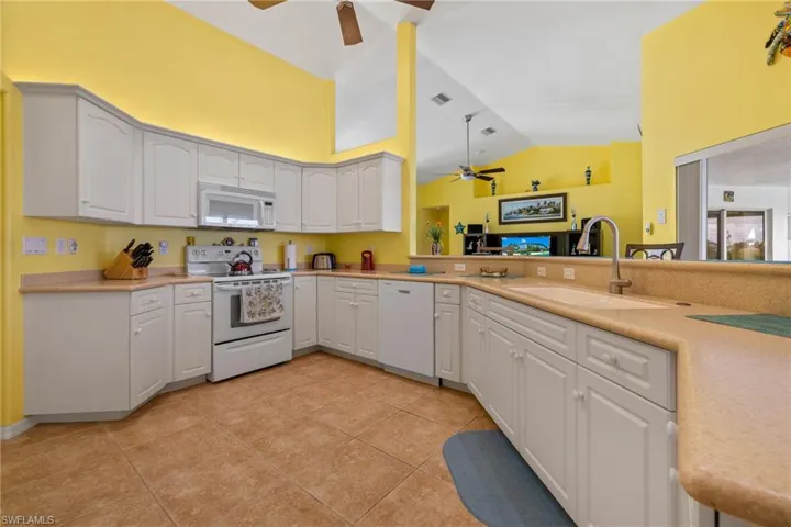 Kitchen with white cabinetry, sink, white appliances, and kitchen peninsula