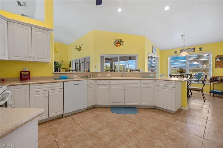Kitchen featuring light tile patterned floors, sink, dishwasher, hanging light fixtures, and white cabinets