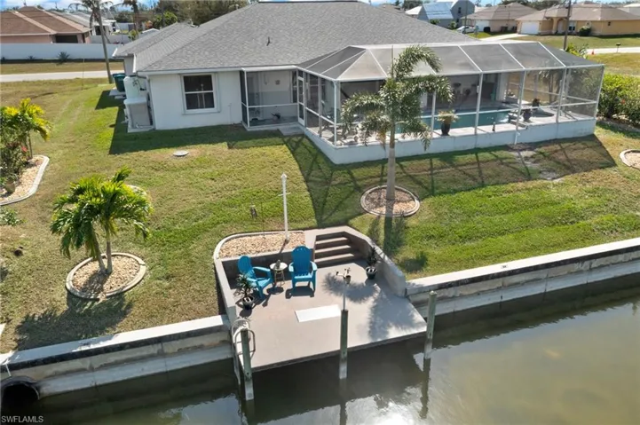 Rear view of house with a patio area, a lawn, a water view, and glass enclosure