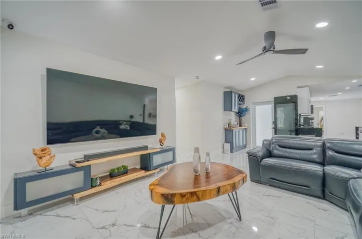 Living room with marble look tile flooring, recessed lighting, lofted ceiling, and ceiling fan