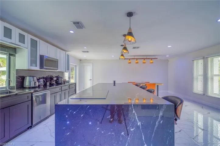 Kitchen featuring light marble finish flooring, appliances with stainless steel finishes, a sink, recessed lighting, and plenty of natural light