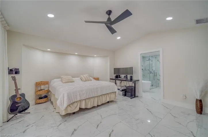 Bedroom featuring recessed lighting, vaulted ceiling, marble finish flooring, baseboards, and ensuite bathroom