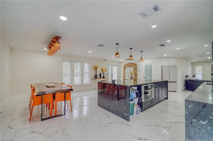 Kitchen with white refrigerator, recessed lighting, light marble finish floors, stainless steel oven, and baseboards
