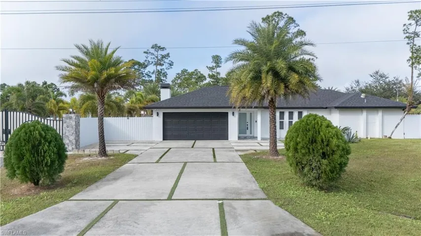 Ranch-style home with driveway, an attached garage, stucco siding, and a chimney