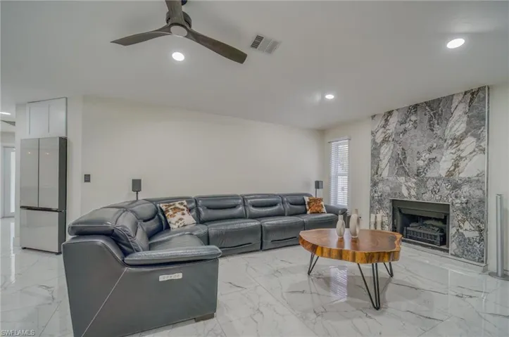 Living room with recessed lighting, light marble finish floors, a ceiling fan, and a premium fireplace