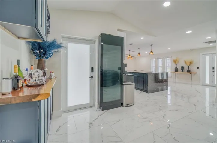 Kitchen with vaulted ceiling, recessed lighting, a center island, hanging light fixtures, and light marble finish flooring