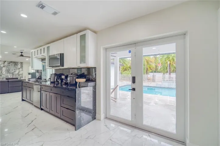Kitchen with white cabinets, dishwasher, light marble finish floors, open floor plan, and recessed lighting
