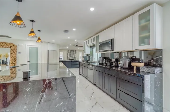 Kitchen with stainless steel appliances, dark stone counters, white cabinetry, a ceiling fan, and recessed lighting