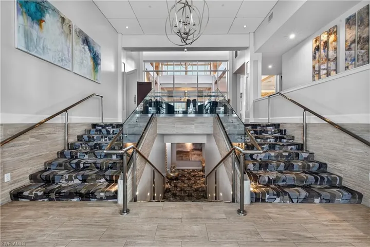 Staircase featuring suspended lighting and wainscoting