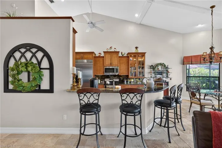 Kitchen featuring wood finish cabinetry, a kitchen bar, stainless steel appliances, a peninsula, and stone tile floors