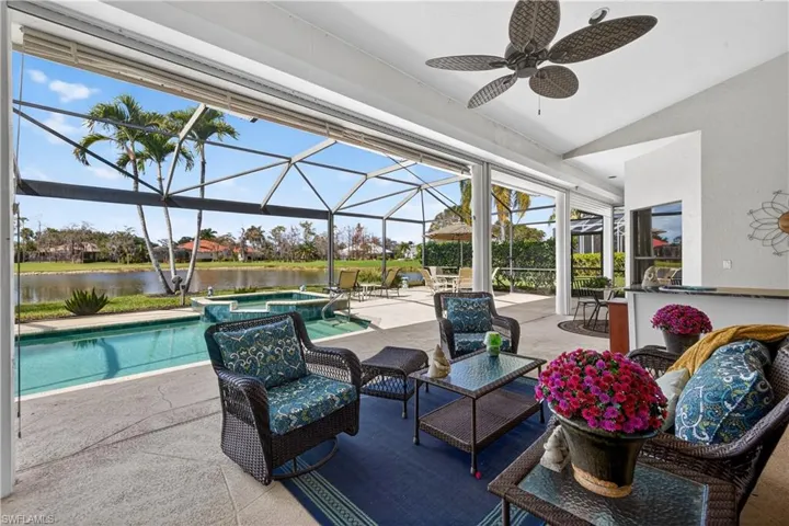 View of patio / terrace with a lanai, a sunroom, a pool with connected hot tub, a water view, and an outdoor lounge area with bar