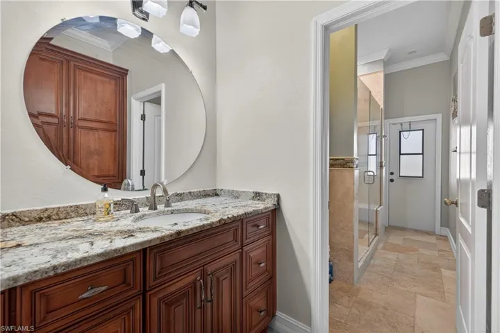 Full bathroom with ornamental molding, vanity, a stall shower, and light stone finish floors