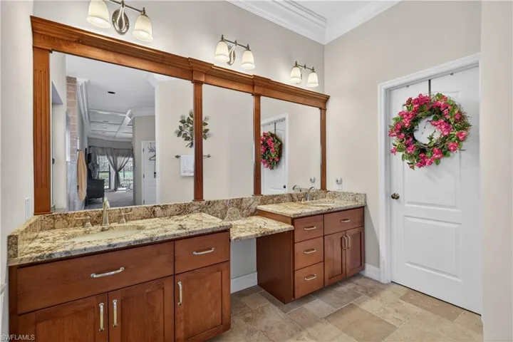 Bathroom featuring crown molding, vanity, and stone tile floors