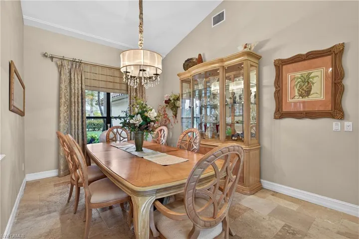 Dining room featuring stone tile floors, vaulted ceiling, and suspended lighting