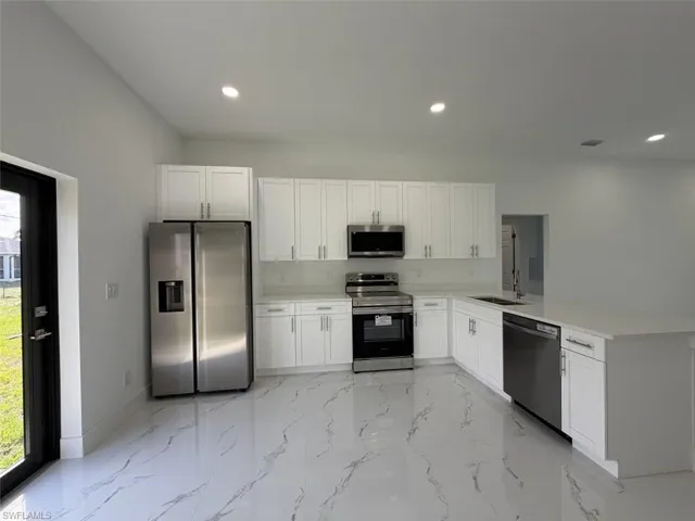 Contemporary kitchen featuring white shaker cabinetry, stainless steel appliances, white quartz countertops, and large format porcelain tile flooring