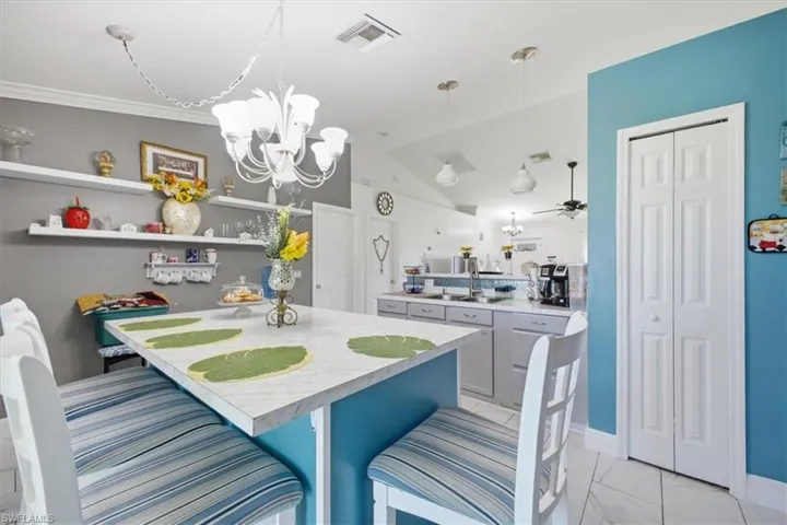 Kitchen featuring a central island with countertop seating, white tile flooring, and vaulted ceilings