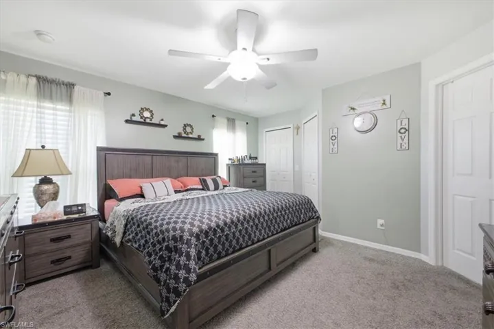 Carpeted room featuring a ceiling fan with integrated lighting, multiple windows with blinds, and white paneled doors