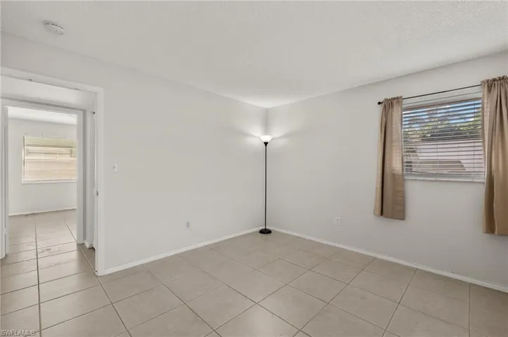 Unfurnished room featuring light tile patterned floors, baseboards, and a textured ceiling