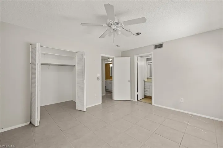 Unfurnished bedroom featuring a closet, a textured ceiling, visible vents, and a ceiling fan