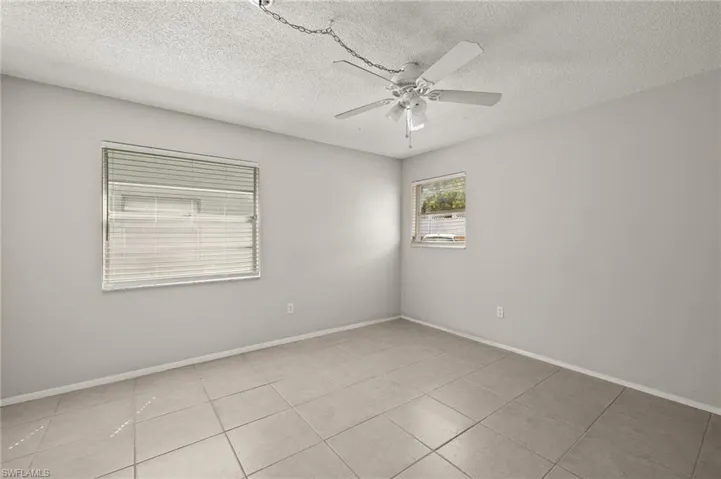Tiled spare room with a textured ceiling, baseboards, and ceiling fan