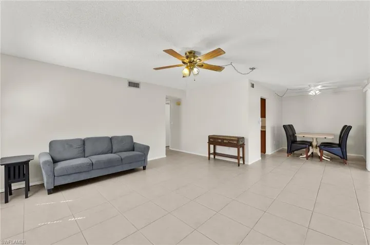 Living area featuring light tile patterned floors, visible vents, a textured ceiling, and ceiling fan