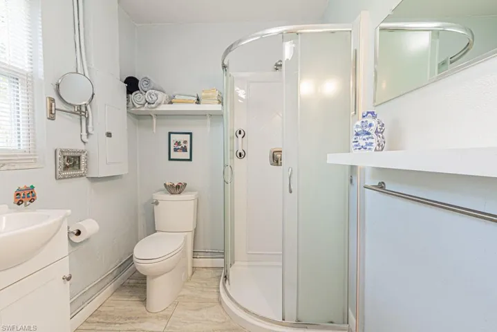 Bathroom with a shower with shower door, vanity, toilet, and tile patterned floors