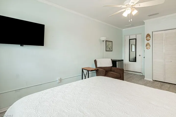 Bedroom featuring light wood-type flooring, ceiling fan, and ornamental molding