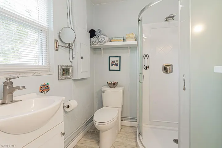 Bathroom featuring a shower with shower door, tile patterned flooring, toilet, vanity, and a baseboard heating unit