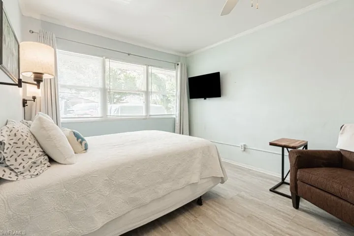 Bedroom featuring wood-type flooring, ceiling fan, and crown molding