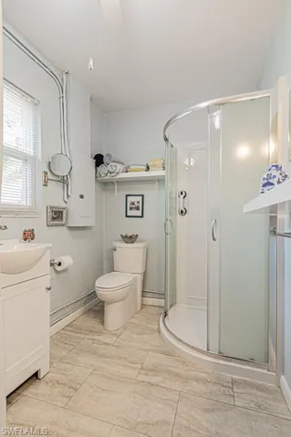Bathroom with a shower with shower door, vanity, tile patterned flooring, and toilet