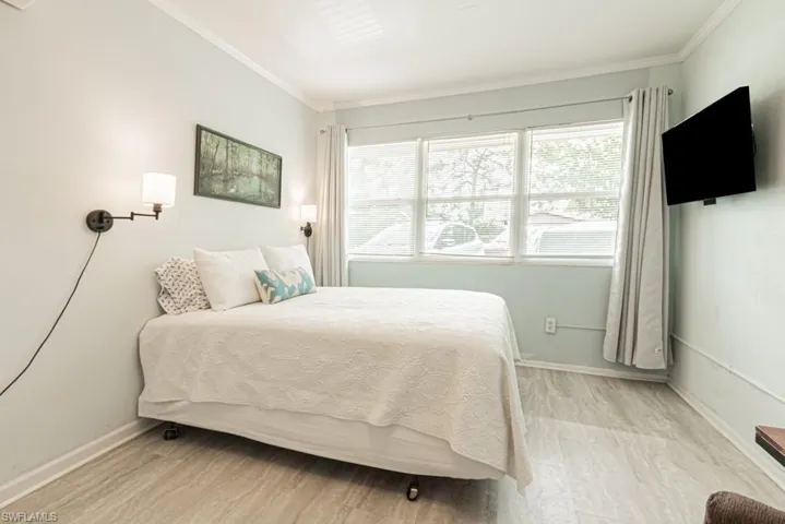 Bedroom with ornamental molding and light hardwood / wood-style floors