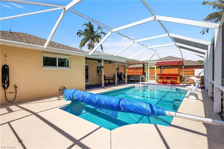 View of swimming pool featuring a covered pool, patio surround, a sunroom, and a lanai
