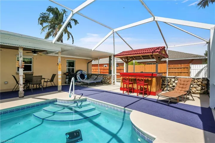 Swimming pool featuring an outdoor bar and dining area, a patio, glass enclosure, and a sunroom