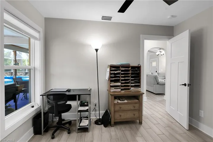 Office space with ceiling fan, wood finish floors, and arched walkways