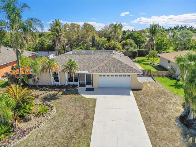 Ranch-style home with driveway, a garage, stucco siding, and view of wooded area