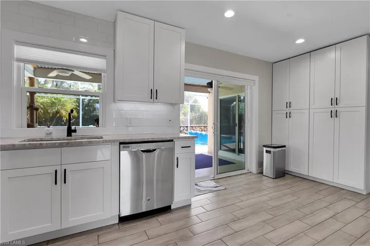 Kitchen with white cabinets, stainless steel dishwasher, a ceiling fan, wood finish floors, and recessed lighting
