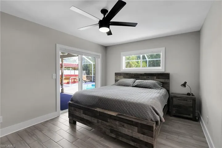 Bedroom with access to exterior, wood finish floors, multiple windows, and ceiling fan