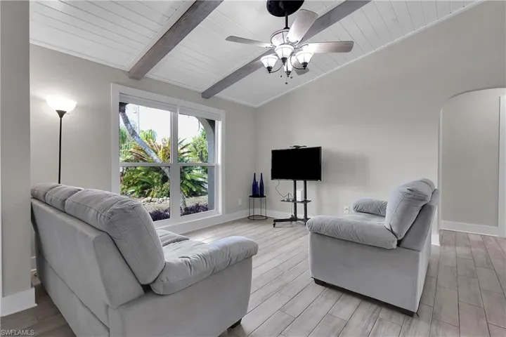 Living area with wood tiled floors, lofted ceiling with beams, ceiling fan, and wood ceiling